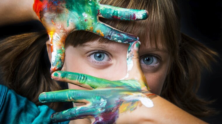 a girl looks through her with paint besmeared hands